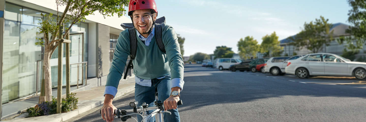 Mann mit Helm und Rucksack auf dem Weg durch eine Stadt