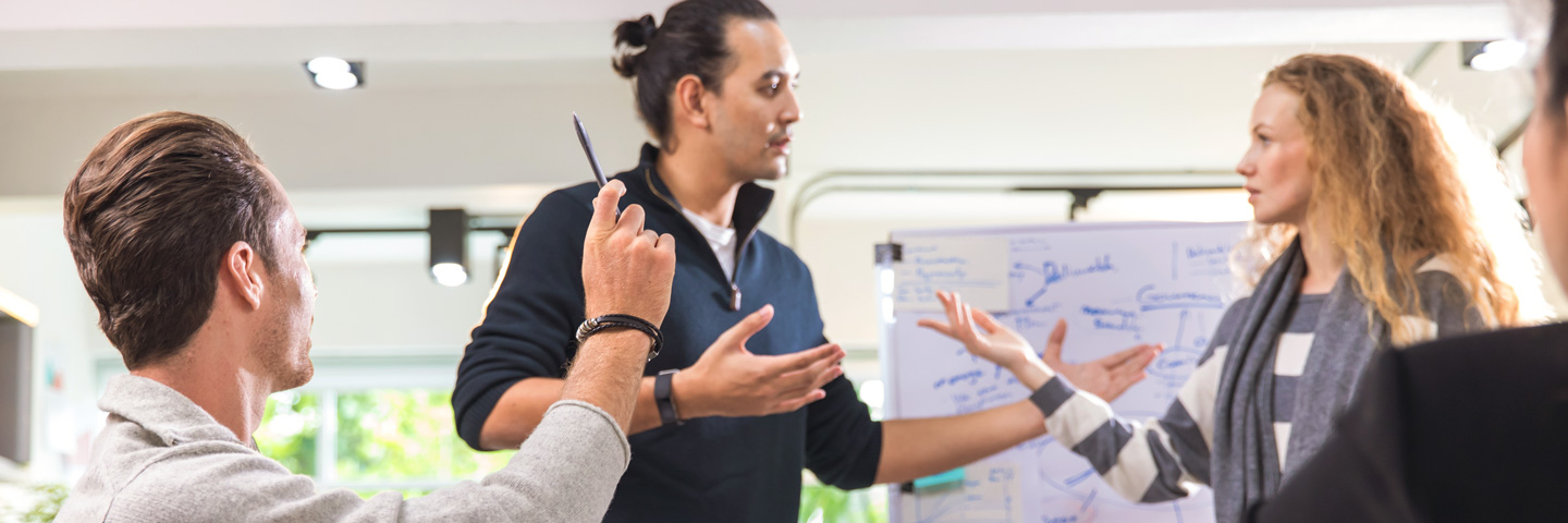 Ein Team vor einem Flipchart in einer lebhaften Diskussion.