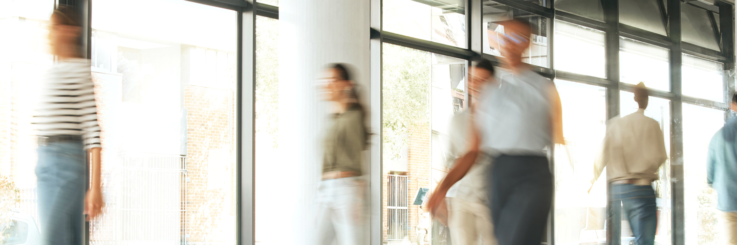 Menschen, die durch einen Büroflur laufen: Viele Rückenschmerzen können mit Bewegung aktiv vermieden werden