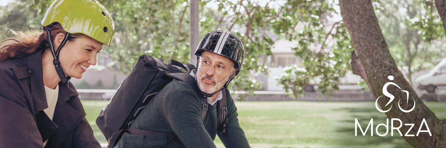 Mit dem Rad zur Arbeit: Eine junge Frau und ein älterer Mann radeln durch einen Park