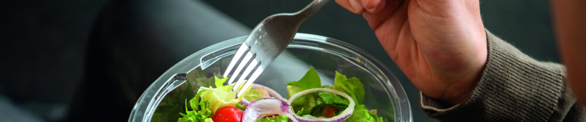 Hand führt eine Gabel in eine Schale Salat
