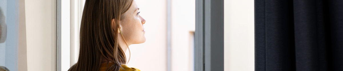 Eine Frau steht am geöffneten Fenster.