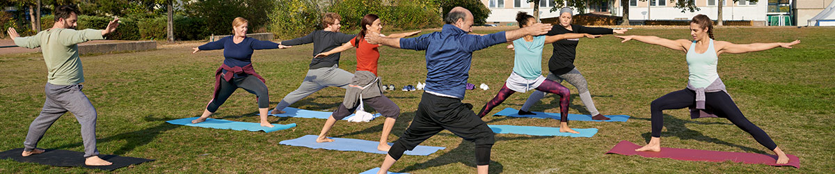 Eine Gruppe macht gemeinsam Yoga-Übungen im Park.