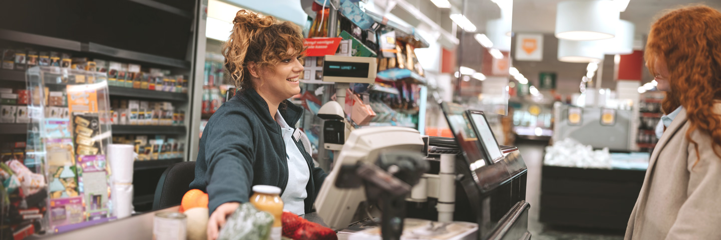Neues bei Minijobs: Minijobberin an einer Supermarktkasse.