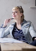 Praktische Tools für Arbeitgeber Nachdenklich lächelnde Frau mit Stift sitzt entspannt an einem Schreibtisch im Büro.