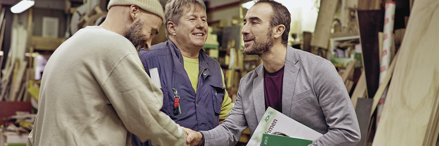 Service für Arbeitgeber Drei Männer arbeiten gemeinsam in einer Werkstatt