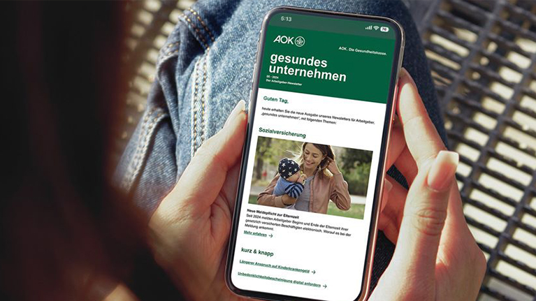 Eine Frau liest über ihr Smartphone den AOK Newsletter.