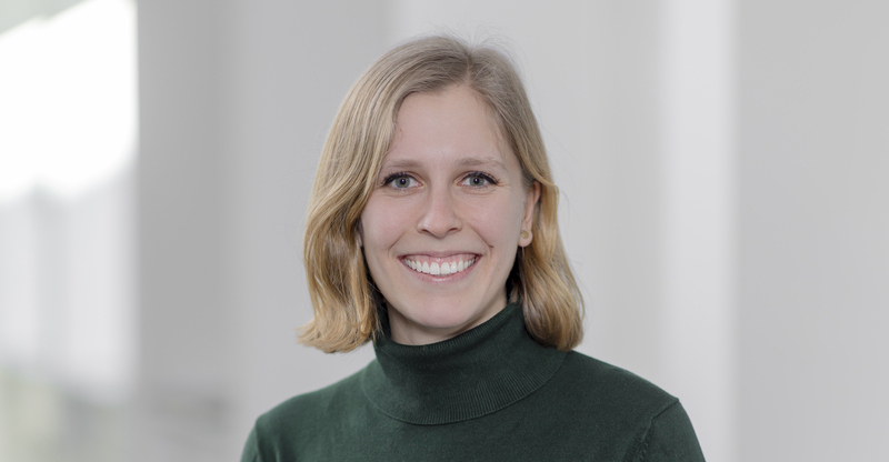 Elisa Dörpinghaus Eine lächelnde, junge, blonde Frau in einem dunkelgrünen Rollkragenpullover.