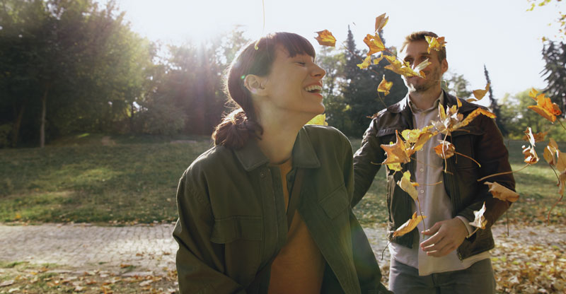 AOK-Mitglied werden: Eine Frau und ein Mann an einem sonnigen Herbsttag im Park, umgeben von Laub AOK-Mitglied werden: Eine Frau und ein Mann an einem sonnigen Herbsttag im Park, umgeben von Laub