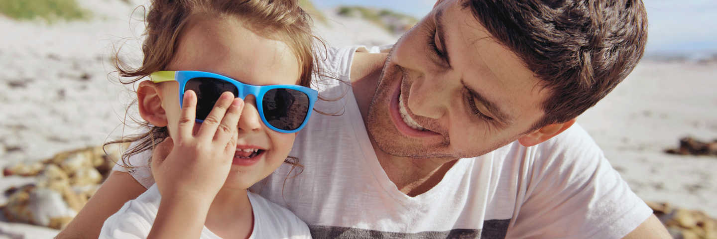 AOK-Mitglied werden: Mann sitzt mit Kind am Strand AOK-Mitglied werden: Mann sitzt mit Kind am Strand