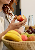 Ernährungstipps: Mitarbeitende stehen ein Obst essend um einen Obstkorb herum.