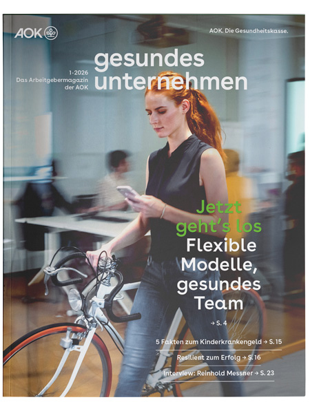 gesundes unternehmen Ausgabe 1-2026: Junge Frau im Büro schaut auf ihr Smartphone während sie ihr Rennrad schiebt