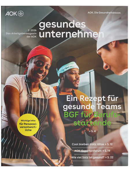 gesundes unternehmen Ausgabe 2-2026: Drei Personen arbeiten zusammen in einer Küche