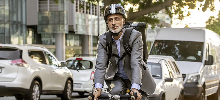 Mit dem Rad zur Arbeit Ein Mann mit Helm und im Anzug fährt auf einem Fahrrad.
