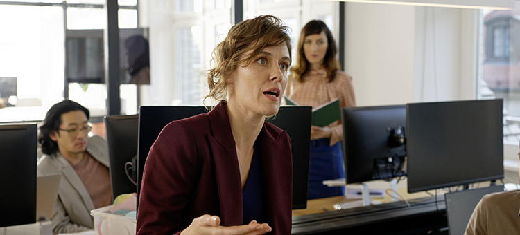Sexuelle Belästigung am Arbeitsplatz verhindern Eine Chefin spricht mit ihrem Team.