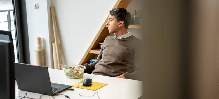 Gesund führen aus der Ferne Ein Mann sitzt in seinem Arbeitszimmer und schaut aus dem Fenster.
