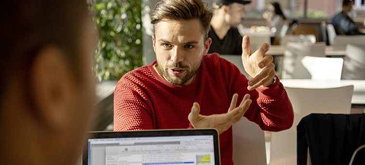 Wer bei seiner Tätigkeit ganz bei der Sache ist, arbeitet im Flow. Ein junger Mann erklärt einem Kollegen etwas.