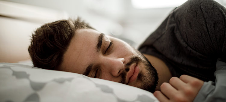 Erholte Mitarbeiter sind gesund und leistungsfähig. Ein Mann liegt schlafend im Bett.