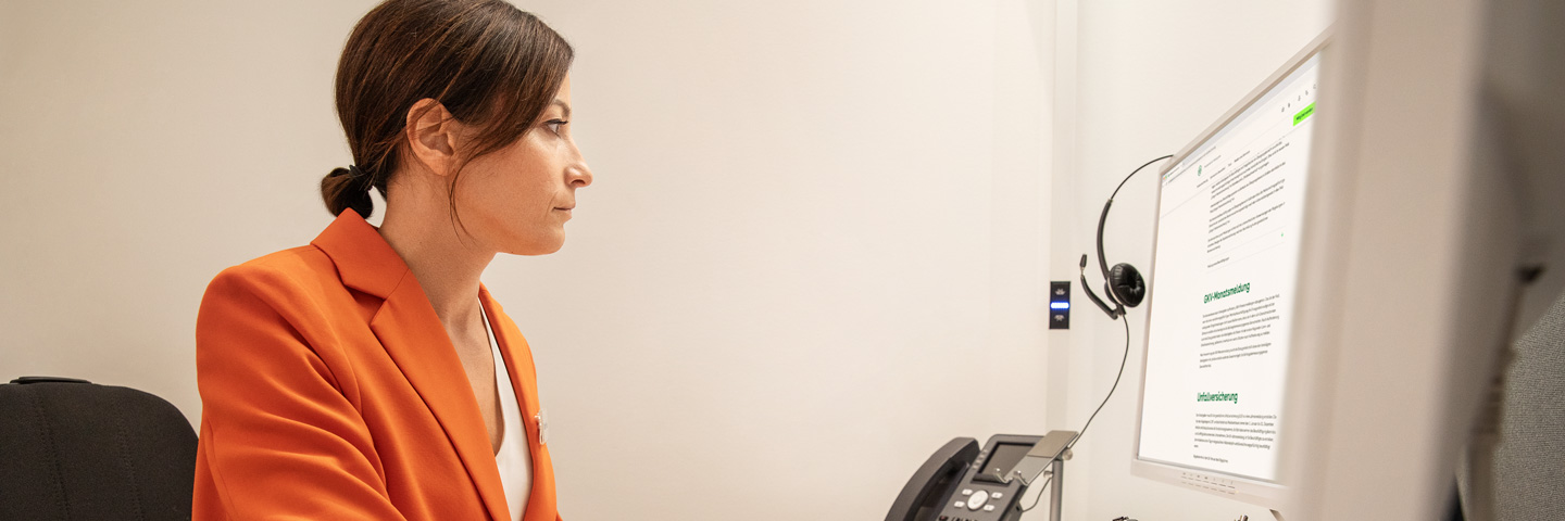 Entgeltabrechnung richtig korrigieren: Eine Frau sitzt an einem Schreibtisch und arbeitet an einem Computer.