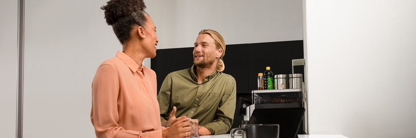 Vertrauen am Arbeitsplatz: Eine Frau und ein Mann stehen in einer Küche und unterhalten sich.