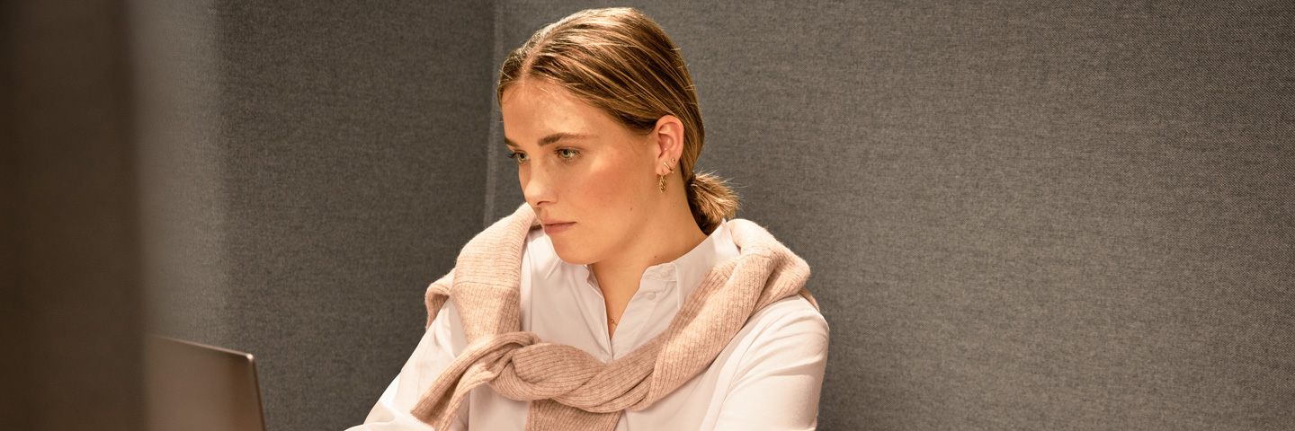 Ruhe am Arbeitsplatz: Eine junge Frau arbeitet konzentriert an einem Laptop in einer ruhigen Arbeitskabine.