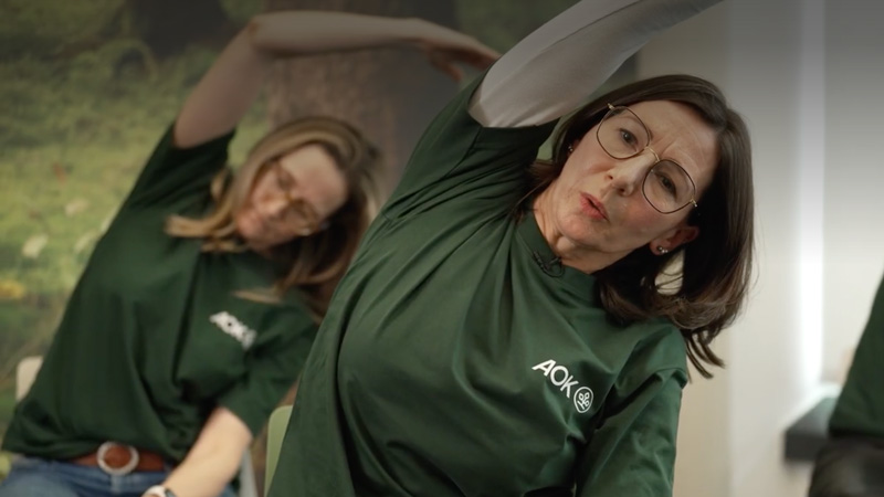 Stuhlyoga: mehrere Frauen beugen sich sitzend zur Seite in einer Yogaübung