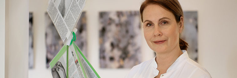 Online-Seminare für Arbeitgeber in Gesundheitsberufen Mitarbeiterin im Gesundheitsberuf vor Lektüre in einem Wartebereich.