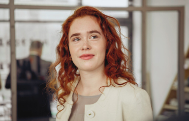 Junge, rothaarige Frau mit optimistisch-freundlichem Blick.