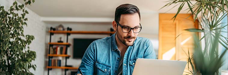 Omline-Seminar „Gesund im Homeoffice“ Ein Arbeitnehmer erledigt ganz entspannt seine Aufgaben am Notebook.
