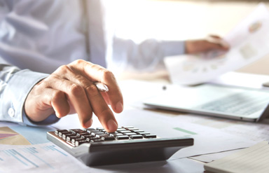 Online-Seminar „Praxistipps für die Entgeltabrechnung“: Mann am Schreibtisch tippt auf einem Taschenrechner