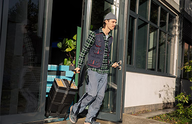 Online-Seminar „Ende von Beschäftigungen“: Mann mit Rollkoffer verlässt ein Gebäude.