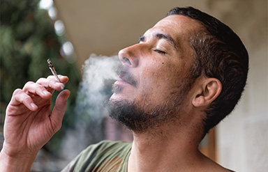 Online-Seminar „Cannabis und Suchtprävention im Unternehmen“: Person raucht einen Joint mit geschlossenen Augen.