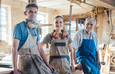 Online-Seminar „GenZ und Babyboomer“: Ein junger Mann, eine junge Frau und ein älterer Mann im Handwerksbetrieb