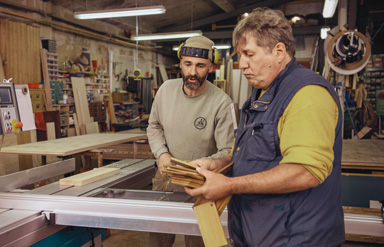 Online-Seminar „Personaleinsatz bei anderen Arbeitgebern“: Zwei Männer besprechen sich in einer Werkstatt.