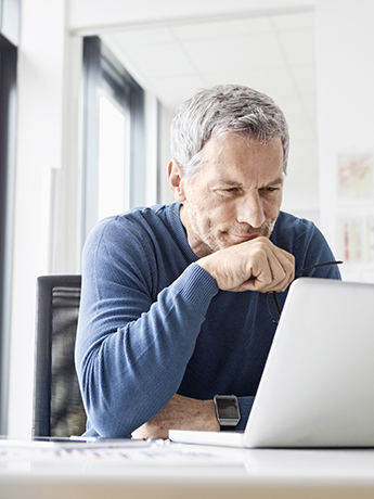 Ein Mitarbeiter informiert sich über Meldungen in der Sozialversicherung Eine Person sitzt vor einem Laptop