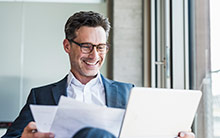 Online-Training Basiswissen Sozialversicherung Ein Mann schaut lächelnd in seinen Laptop.