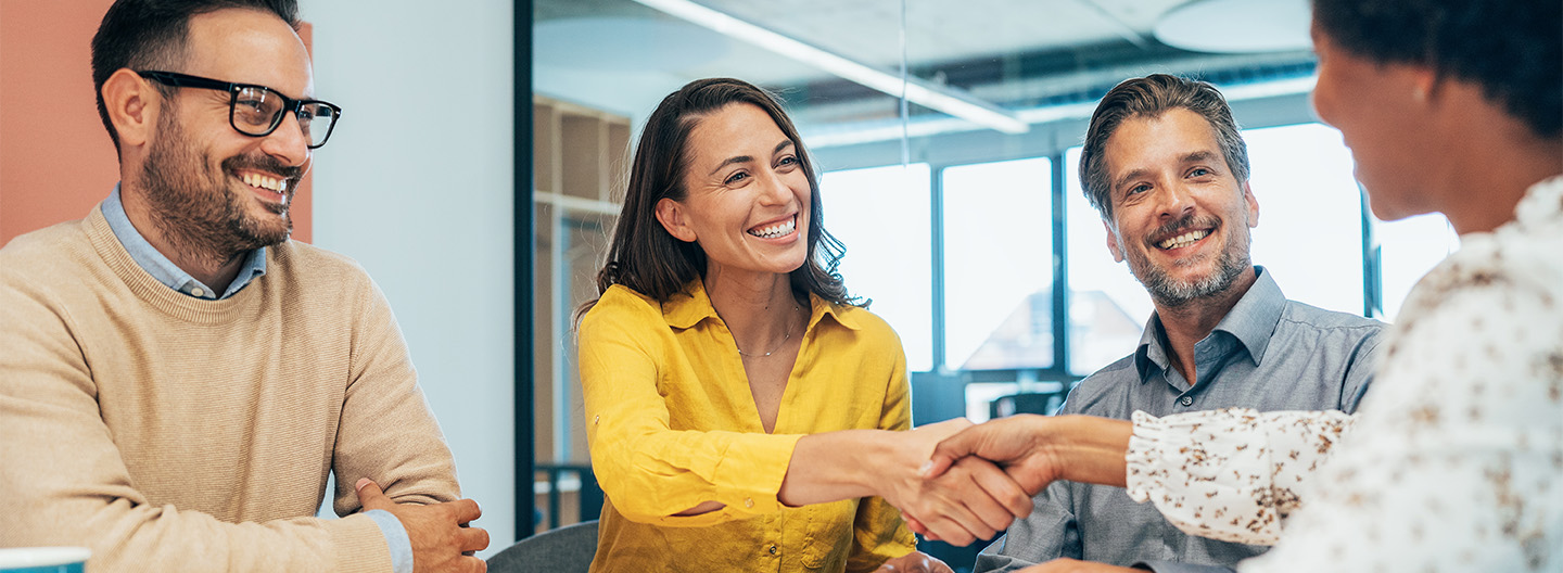 Onboarding für Fachkräfte: Ein Team begrüßt eine neue Kollegin freundlich mit Handschlag