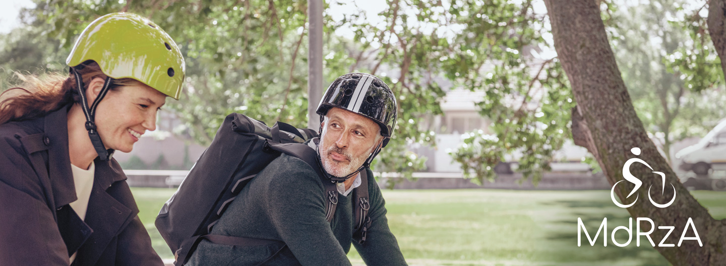 Mit dem Rad zur Arbeit: Eine junge Frau und ein älterer Mann radeln durch einen Park