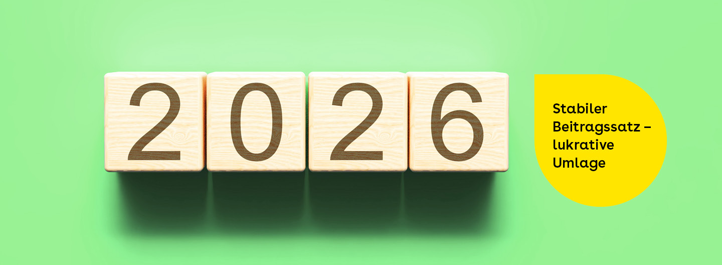 Beitragssatz 2026: Holzbausteine mit der Jahreszahl 2026 neben einem gelben Textfeld mit der Aufschrift „Stabiler Beitragssatz – lukrative Umlage“ auf grünem Hintergrund.
