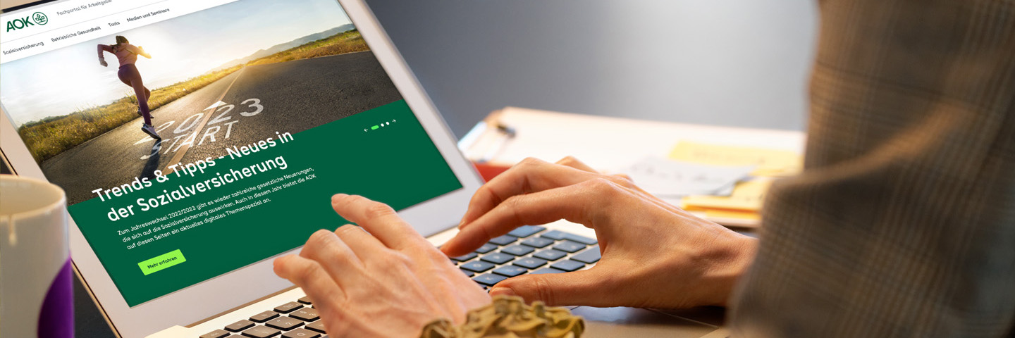 Meldung zur Sozialversicherung Geöffneter Laptop mit Händen über der Tastatur zeigt AOK-Seite.