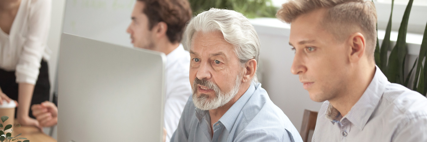 Meldungen zur Sozialversicherung: Zwei Männer schauen gemeinsam auf einen Bildschirm Meldungen zur Sozialversicherung: Zwei Männer schauen gemeinsam auf einen Bildschirm