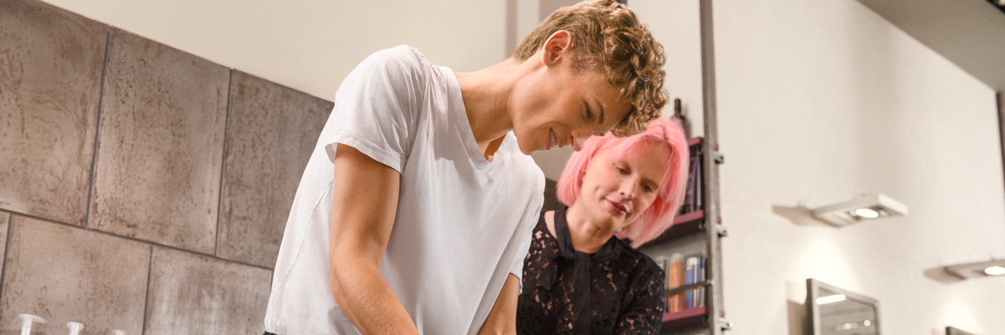 Erfolgreich ausbilden: Auszubildender wäscht Kundin die Haare in einer Fahrrad-Werkstattin einem Friseurbetrieb