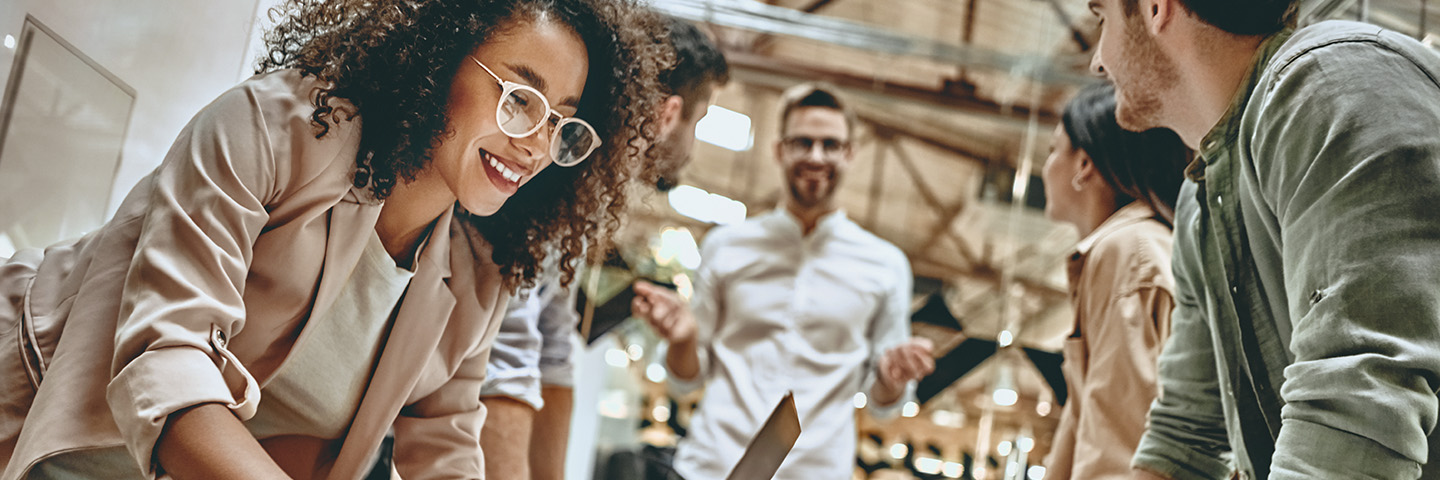 Urlaubsplaner 2024 Ein Team hat sich um einen Stehtisch gruppiert und diskutiert