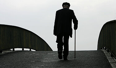 Älterer Mensch geht über Brücke (Symbolbild)