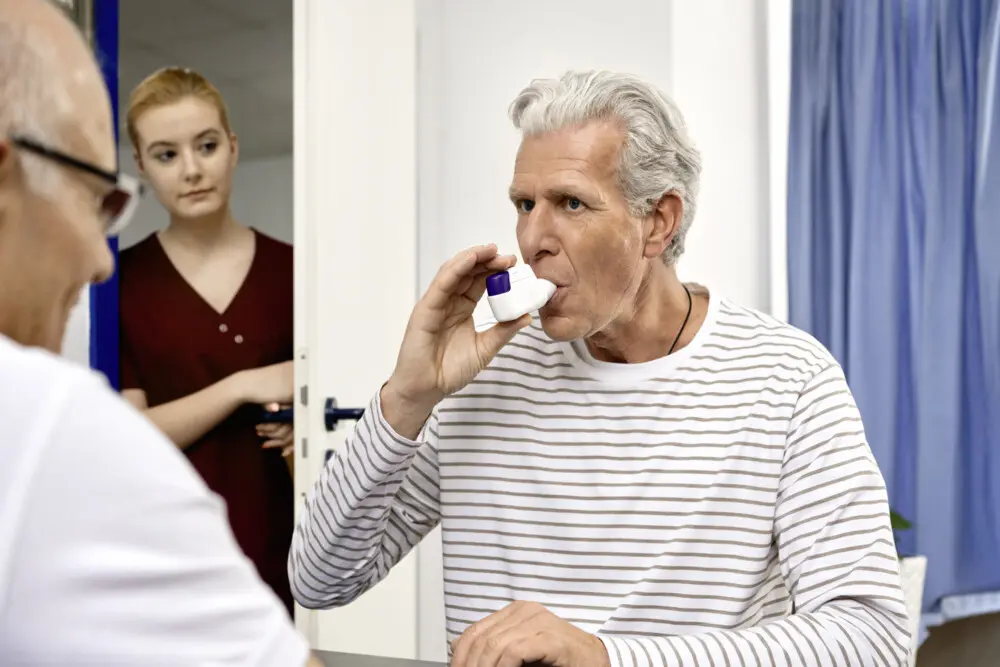 Arzt und Patient, Patient nimmt Asthma- oder COPD-Medikament ein. (Symbolbild)