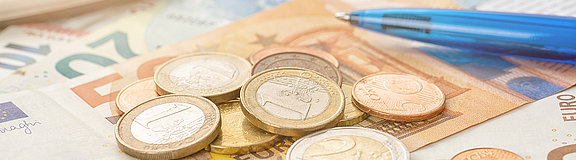 Münzgeld und Euro-Scheine mit einem Taschenrechner (Symbolbild)