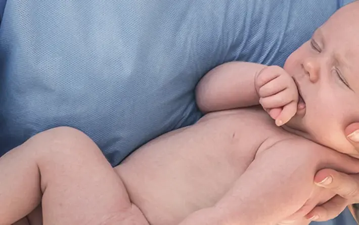 Hebamme hält neugeborenes Baby im Arm