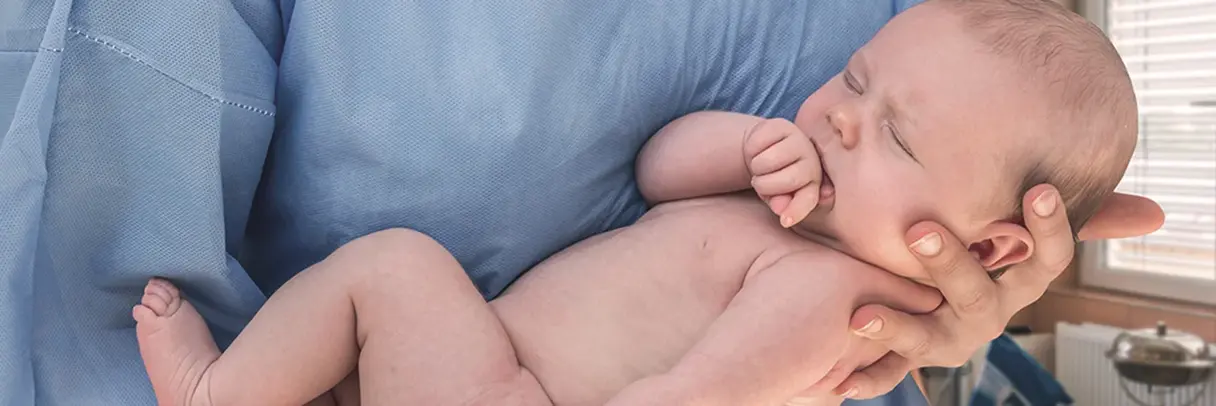 Hebamme hält neugeborenes Baby im Arm