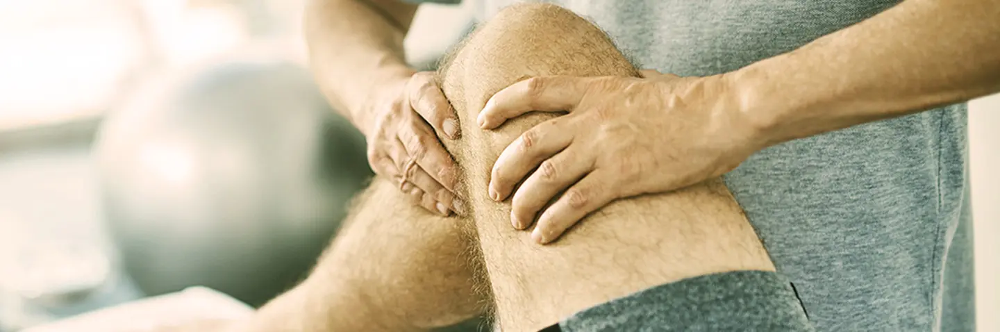 Therapeut behandelt Knie eines Patienten