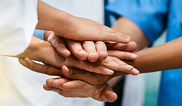 Medizinisches Personal legt Hände übereinander